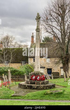 War memorial in the churchyard of St Mary Magdalene, Geddington, Northamptonshire, UK; commerates those killed or missing in WW1 and WW2 Stock Photo