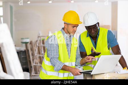 Male engineers using laptop in building site Stock Photo