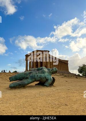 A bronze statue of fallen Ikaro on the background the Concorde temple, Agrigento, Sicily, Italy Stock Photo