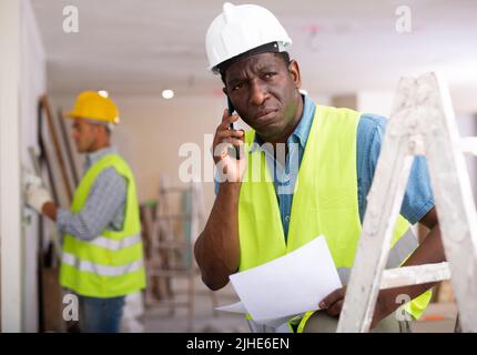 Man builder having telephone conversation in construction site Stock Photo