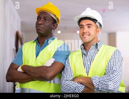 Portrait of two positive builders standing in construction site Stock Photo