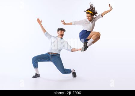 Portrait of young happy couple, man and woman, dancing isolated over white studio background. Excitement Stock Photo
