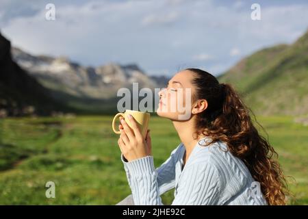 Side view portrait of a relaxed woman enjoying of a coffee cup in the high mountain Stock Photo