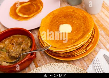 Thin pancakes with butter and machanka of meat with vegetables and mushrooms Stock Photo