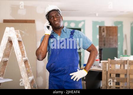 African american builder is talking on a mobile phone Stock Photo