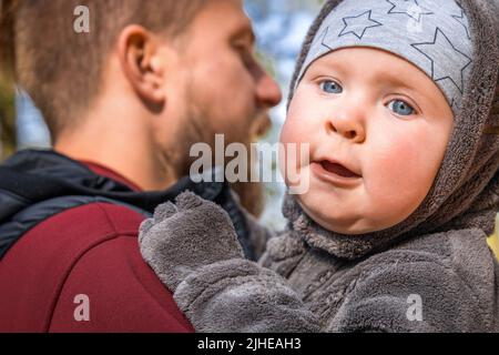 Close-up portrait of little baby boy in the arms of his father outdoor Stock Photo