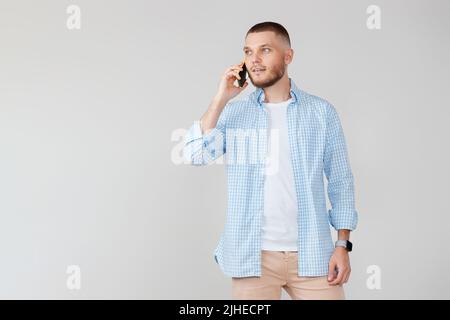 Handsome young man using cell phone while standing Stock Photo