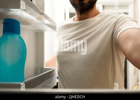 Man looking for food in the refrigerator. Concept of rising food prices, of impoverishment of the poor. Stock Photo