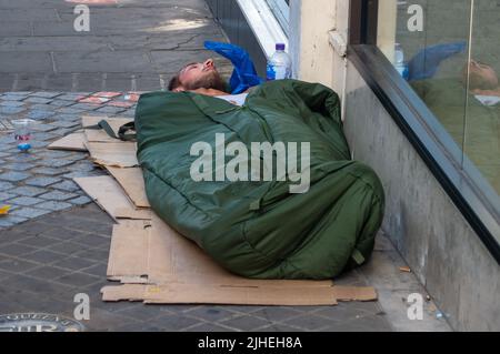 Windsor, Berkshire, UK. 18th July, 2022. A homeless man sleeps on a street in Windsor. The Met Office has declared a UK National Emergency by issuing the first ever Level 4 Red Alert warning for most of the UK. Record temperatures are expected today and tomorrow as the heatwave worsens. Credit: Maureen McLean/Alamy Live News Stock Photo