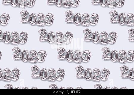 Repetitive pattern made of 2023 silver inflatable balloons on a blue pastel background. New Year's creative backdrop. Stock Photo