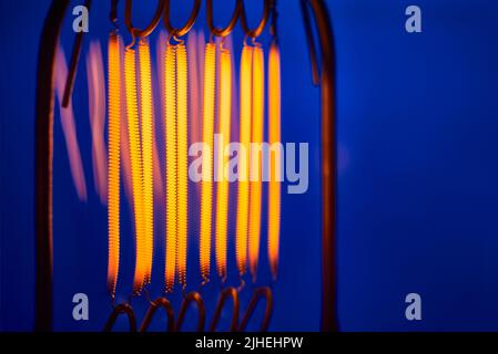 tungsten filament of high power incandescent lamp on blue background close up Stock Photo