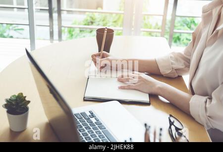 new normal, a businesswoman useing notebook and computer to work for a company Via the internet on your desk at home, vintage effect Stock Photo