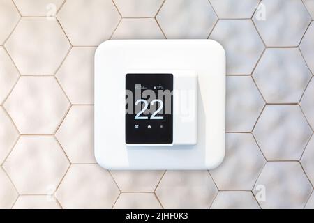 Smart thermostat hanging on an ecofriendly wall made of recycled material Stock Photo