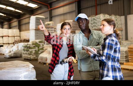 Workers and manager discussing completed work in large warehouse Stock Photo