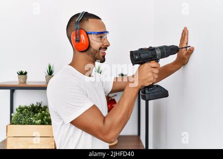 Young hispanic man smiling confident using drill at home Stock Photo