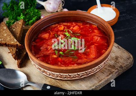 Traditional ukrainian borscht with green onion and sour cream. Delicious beet soup in bowl with rye bread Stock Photo