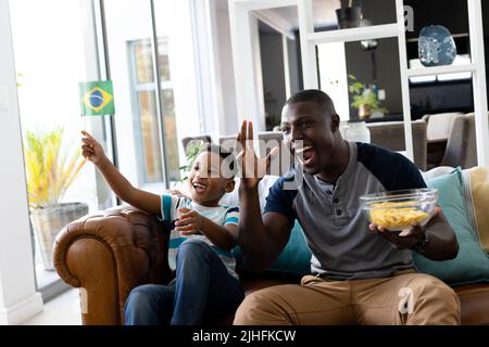 Image of african american father and son playing watching tv Stock Photo