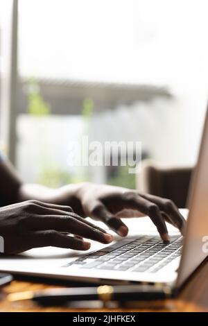 Vertical image of hands of african american man working on laptop Stock Photo