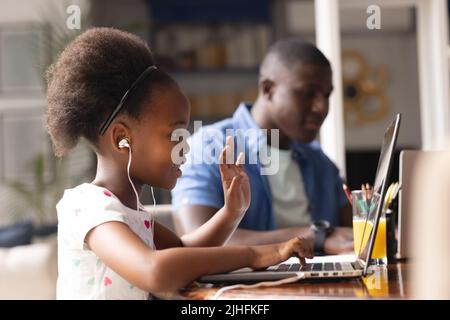 Image of african american father and daughter having online lessons and working together Stock Photo