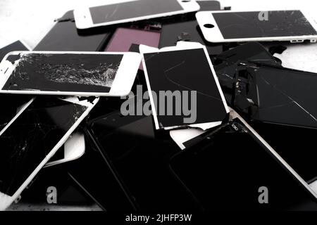 Prague, CZ - 16 January 2022:  Heap, A lot of used broken  iPhone Screens on white bg. Crashed Screen Glass Lcd.  Gadget parts lying one on top of ano Stock Photo