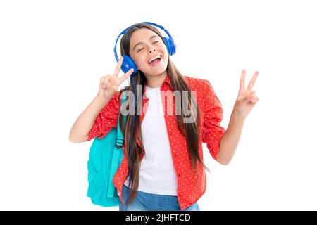 School leisure. Amazed child singing. School girl in headphones on isolated studio background. School and music concept. Stock Photo