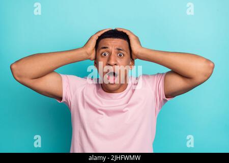 Photo of funky impressed young man dressed pink t-shirt arms head open mouth isolated turquoise color background Stock Photo