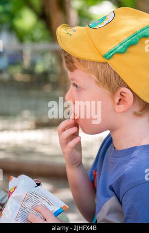 Cute little boy eating chips in the park Stock Photo