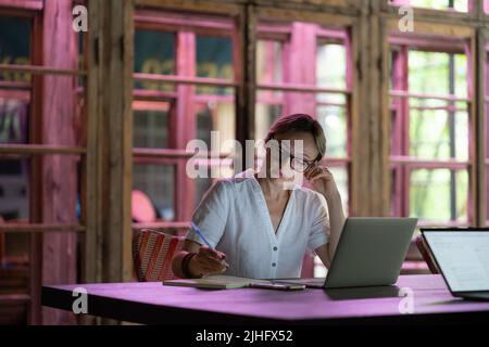 Focused woman freelancer sitting at workplace in coworking space, working on laptop Stock Photo