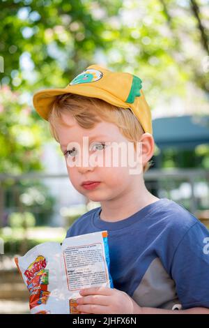 Cute little boy eating chips in the park Stock Photo