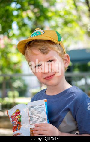 Cute little boy eating chips in the park Stock Photo