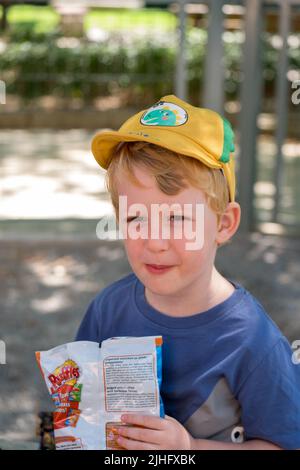 Cute little boy eating chips in the park Stock Photo