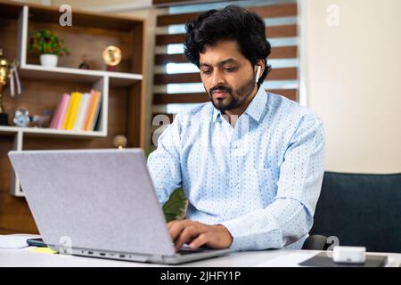 Thoughtful Young corporate employee working laptop while sitting at office - concept of work lifestyle, hard working and dedication Stock Photo