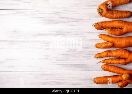 Ugly carrots lie on a light wooden surface Stock Photo