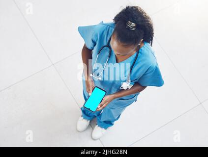 Above african american woman doctor using a smart phone while standing and working in the office. Using wireless technology to diagnose and treat Stock Photo