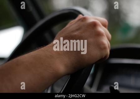 Defocus male hand holding steering wheel. A man's hand handle steering wheel car for driving. Traffic jam, driving car on highway, close up of hands Stock Photo