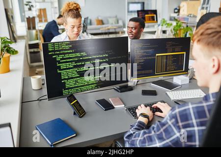 Multiethnic IT specialist working with program on monitors at office desk at IT company Stock Photo