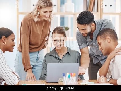 Group of happy diverse colleagues brainstorming together on laptop in an office boardroom. Caucasian businesswoman meeting to explain ideas and Stock Photo