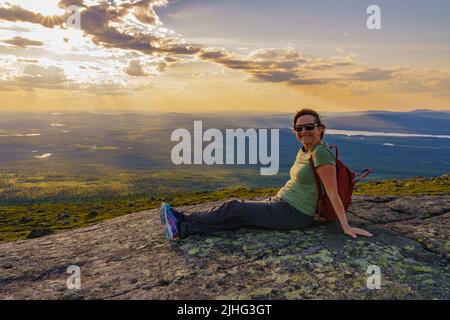 Woman sitting on mountain enjoying the view from Mount Dundret over Laponia, Gällivare county, Swedish Lapland, Sweden