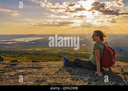 Woman sitting on mountain enjoying the view from Mount Dundret over Laponia, Gällivare county, Swedish Lapland, Sweden