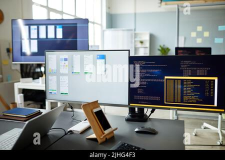 Horizontal image of computer monitors with programs and computer codes on monitors standing on workplace of programmer Stock Photo