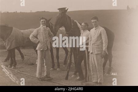 Queen's Own West Kent Yeomanry, early 20th century. Three soldiers standing with a row of army horses. One horse has been dressed with a soldier's cap (with the West Kent Yeomanry cap badge of a prancing horse), a bandolier and a rifle. One soldier is uniform trousers & a shirt, the others are wearing what looks like linen suits (the man on the left appears to also be in a pair of slippers). The photograph was taken by Wessex Photo Co., Bridgewater Stock Photo