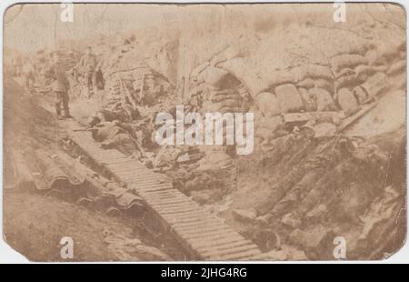 First World War trench in the lull between fighting. German soldiers are standing in the trench towards the back of the image and bodies of the fallen are in the foreground. Shelters constructed out of sandbags are to the right of the trench (a German soldier is looking out of one) and the floor is partly covered by duckboards Stock Photo