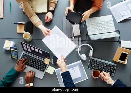High angle view of team of programmers developing new software for virtual reality glasses sitting at table at meeting Stock Photo