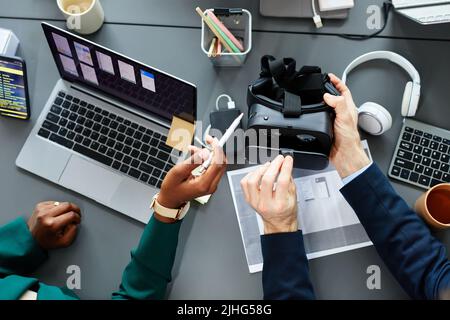 High angle view of programmers testing new virtual reality glasses at table using laptop and smartphone Stock Photo