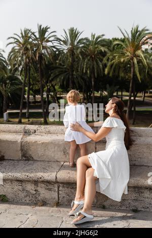 Woman in summer dress touching baby on Puente Del Mar bridge in Valencia Stock Photo