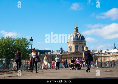 People walking across Pont des Arts or Passerelle des Arts  a pedestrian bridge in Paris taken from low level with the dome of Institut de France Stock Photo