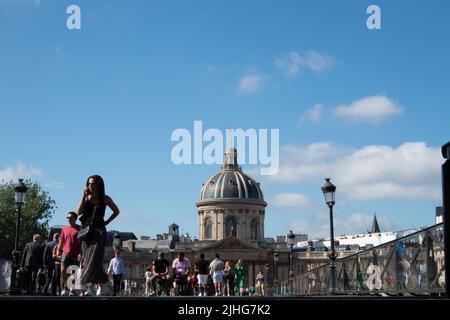 People walking across Pont des Arts or Passerelle des Arts a pedestrian bridge in Paris taken from low level with the dome of Institut de France Stock Photo