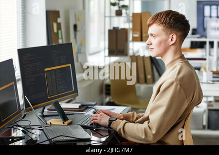Young computer programmer working on website project in software developing on desktop computer at company Stock Photo