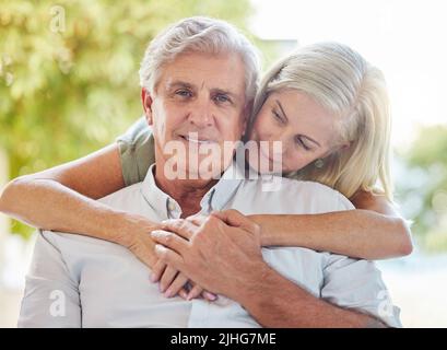A happy mature caucasian couple embracing and showing love while relaxing together at home. Retired couple bonding while sitting together Stock Photo