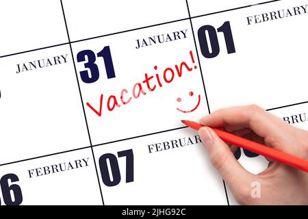 31st day of January. A hand writing a VACATION text and drawing a smiling face on a calendar date 31 January. Vacation planning concept. Winter month, Stock Photo